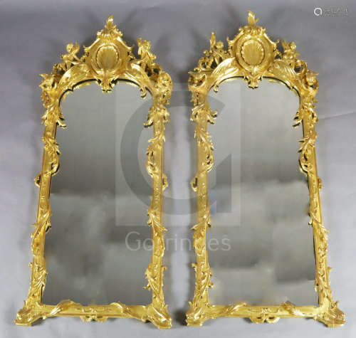 A pair of 19th century French carved giltwood wall ***rors, with scallop and scroll crests flanked