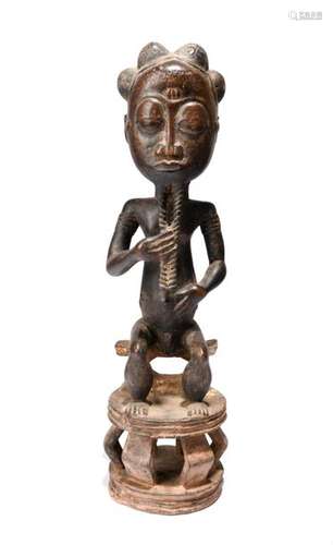 A Baule seated male figure. Ivory Coast. With pigm…