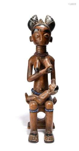 A Fante maternity figure. Ghana. Seated on a stool…