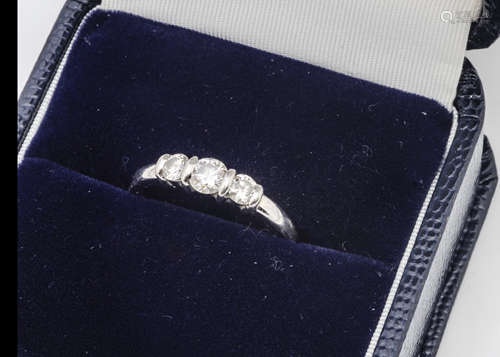 A platinum and diamond three stone ring, the brilliant cuts in bracket setting, on a rounded