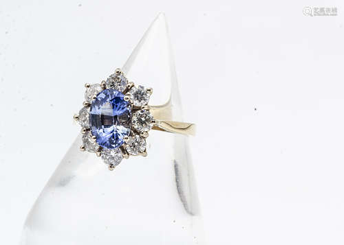 An 18ct gold Ceylon sapphire and diamond cluster ring, the oval mixed cut stone in four claw setting