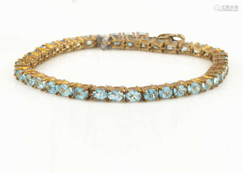 A contemporary 9ct gold blue apatite line bracelet, the oval mixed cut claw set blue gem stones with