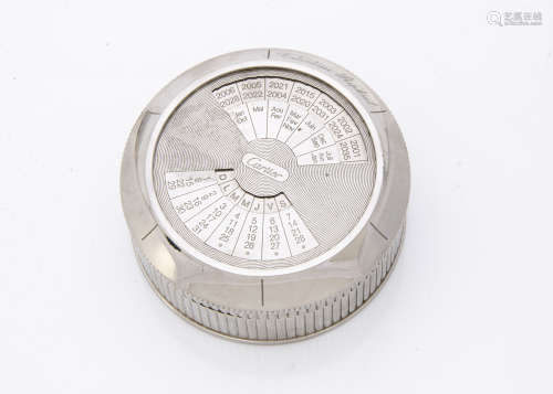 A modern silver plated perpetual desk calendar from Cartier, circular with fluted sides, rotating