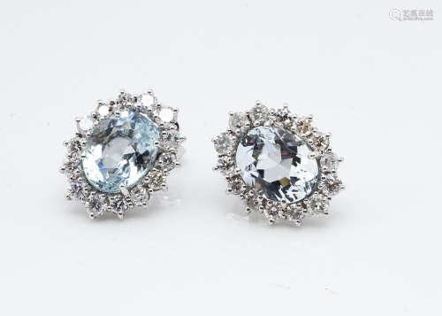A pair of aquamarine and diamond white 18ct gold cluster earrings, central oval claw set aquamarines