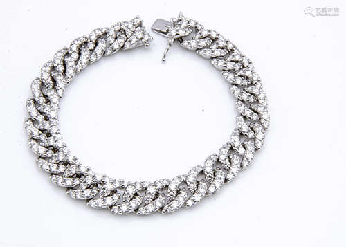 An 18ct white gold diamond set tennis bracelet, the flattened curb links each set with claw set