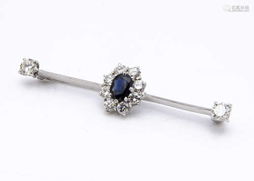 A sapphire and diamond bar brooch, centred with oval claw set sapphire surrounded by brilliant cut