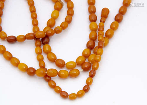 An opera len*** string of uniform oval butterscotch amber beads, 88cm long together, 9.5mm diameter,