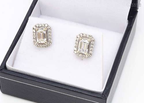 A pair of 18k white gold emerald cut diamond and brilliant cut ear studs, the central stones with