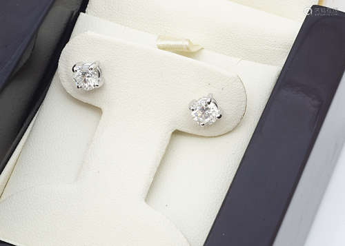 A pair of diamond stud earrings, the brilliant cuts in white claw setting on yellow ***** backs with