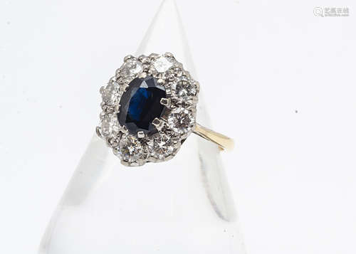 A sapphire and diamond 18ct gold and platinum set cluster ring, the oval claw set sapphire