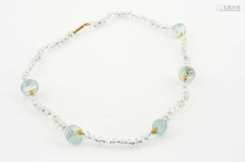 An aquamarine and gold 15ct marked necklace, the faceted circular beads interspersed with gilt metal