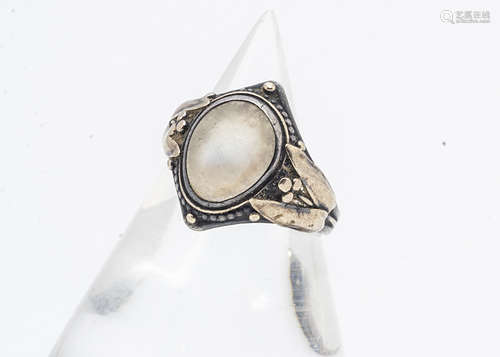 An Arts and Crafts silver and gold moonstone set signet ring, the cabochon oval moonstone within a