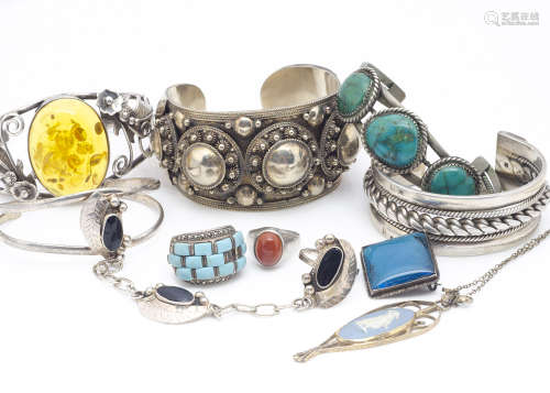 Five silver bangles, including an amber example with floral decoration, another in turquoise, two