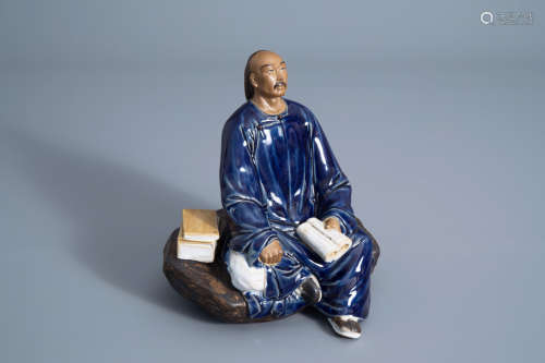 A Chinese Shiwan pottery figure of a man with a book, seal mark, Republic