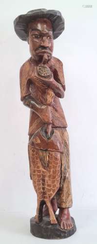 Carved wooden fisherman figure in a black hat, holding catch, 84cm high