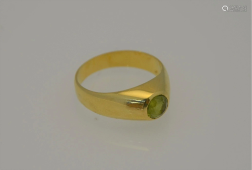 A yellow metal ring set with single circular peridot