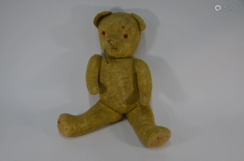 A large gold plush teddy bear with plastic eyes