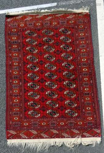 Red ground Eastern Bokhara style rug with thirty elephant foot gulls, 170 x 105cm