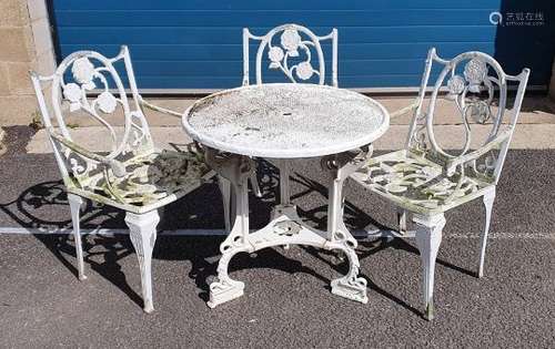 White painted circular aluminium garden table of Tudor rose design with three matching chairs,