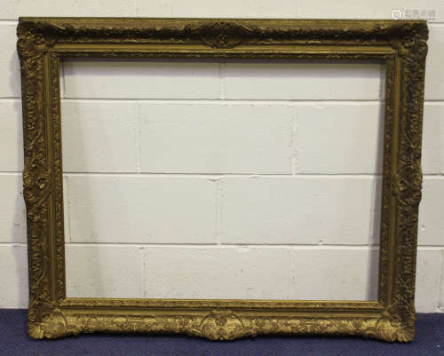 A carved and gilt composition picture frame with foliate scroll decoration, rebate 71.5cm x 92.