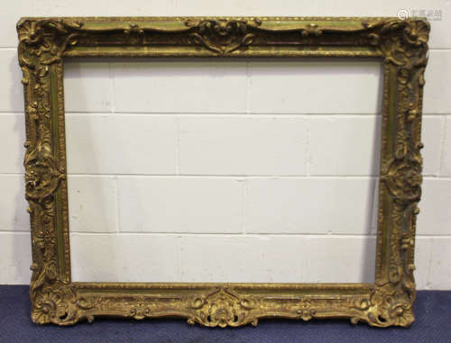 A large gilt composition picture frame with shell and foliate scroll crestings, rebate 106cm x 82cm,