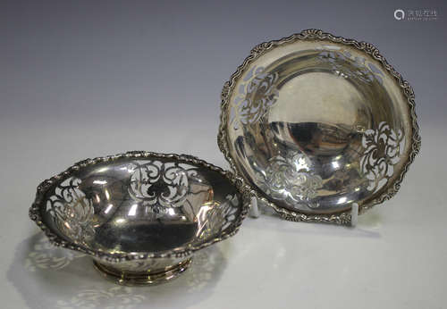 A pair of George V silver circular bonbon dishes, each with pierced foliate panels and cast scroll