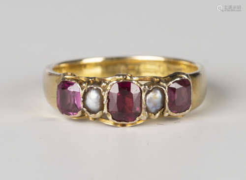 A 9ct gold, garnet and half-pearl ring, mounted with three cushion cut garnets alternating with