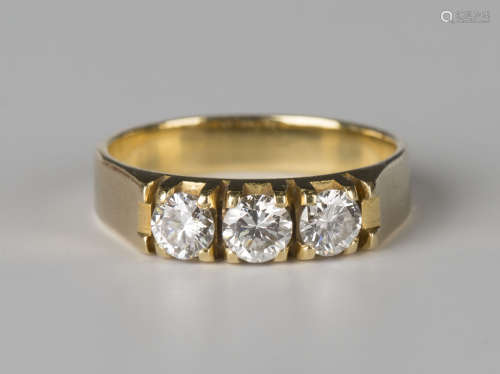 A gold and diamond three stone ring, claw set with circular cut diamonds, detailed '750', ring