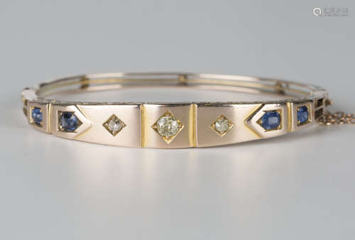 A gold, diamond and sapphire oval hinged bangle, the front mounted with three circular cut