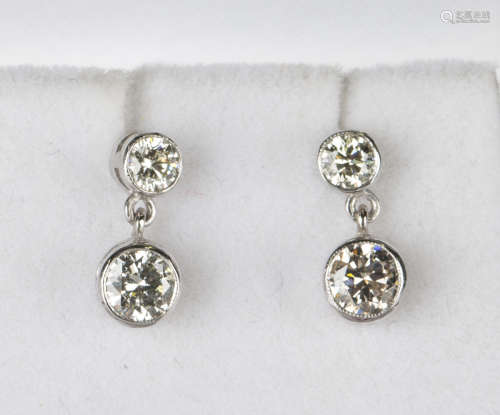 A pair of white gold and diamond pendant earrings, each drop collet set with a circular cut