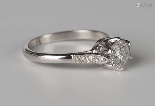 A white gold and diamond ring, claw set with the principal circular cut diamond between diamond