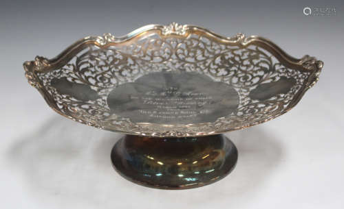 A George V silver footed dish with cast scroll rim and pierced border framing an engraved