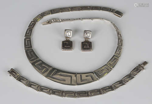 A silver collar necklace in a curved pierced rectangular Greek key style link design graduating in