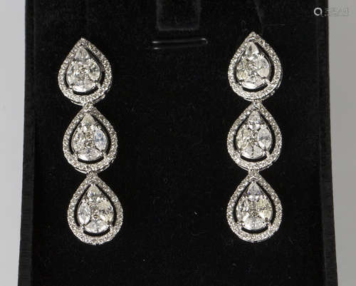 A pair of white gold and diamond triple cluster pendant earrings, each cluster in an open drop