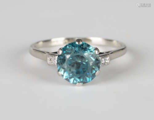 A white gold and platinum ring, claw set with a circular cut blue zircon between two baguette