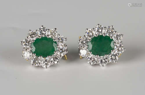 A pair of 18ct two colour gold, emerald and diamond cluster earrings, each claw set with an oval cut