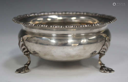 An Edwardian silver circular sugar bowl with scalloped rim, raised on stylized shell feet, London