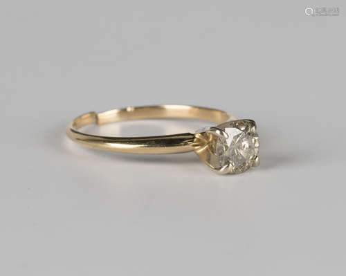 A gold and diamond single stone ring, claw set with a circular cut diamond within a raised