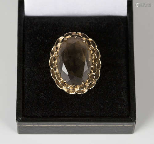 A 9ct gold ring, claw set with an oval cut smoky quartz within a pierced surround, ring size