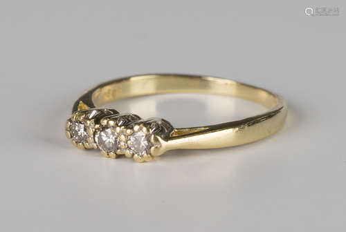 A gold and diamond three stone ring, claw set with a row of circular cut diamonds, the principal