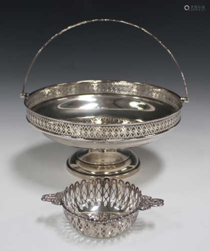A George V silver circular fruit basket with pierced rim and overhead swing handle, on a circular