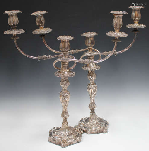 A pair of George III silver candlesticks, each rococo scroll moulded baluster stem decorated in