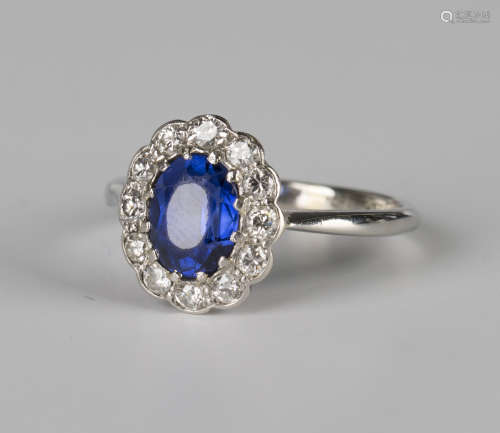 A white gold, platinum, synthetic sapphire and diamond oval cluster ring, claw set with the oval cut