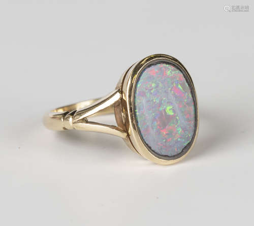 A gold ring, mounted with an oval opal doublet between split shoulders, detailed '9ct', ring size