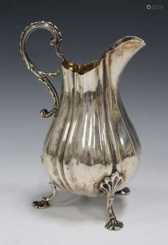 An early Victorian silver milk jug of lobed baluster form with scroll handle, on scallop shell