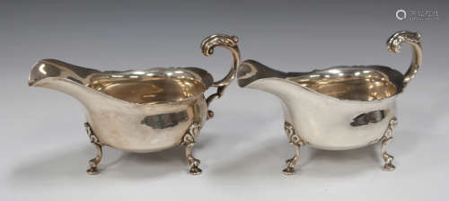 A pair of George V silver sauce boats, each with shaped rim and foliate capped scroll handle, on
