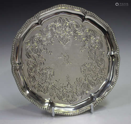 A Victorian silver card salver with beaded shaped rim and engraved foliate band, raised on three