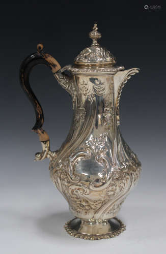 A late Victorian silver hot water jug of baluster form with domed hinged lid and finial, decorated