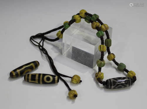 A Tibetan bead necklace, hung with a banded agate dzi bead, length 33.cm, together with two other