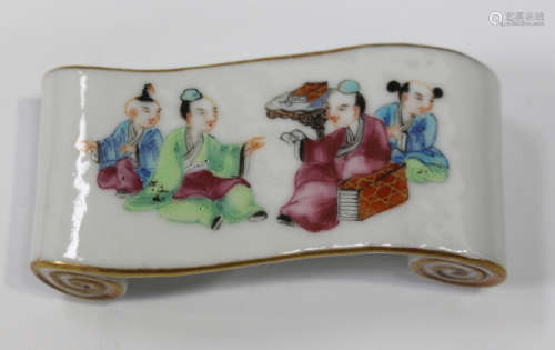 A Chinese famille rose porcelain brush rest, late Qing dynasty, of scroll form, the top painted with
